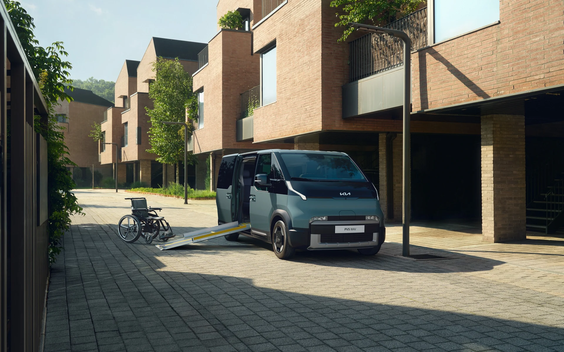 Kia PV5 WAV s vysunutou boční rampou a invalidním vozíkem na ulici