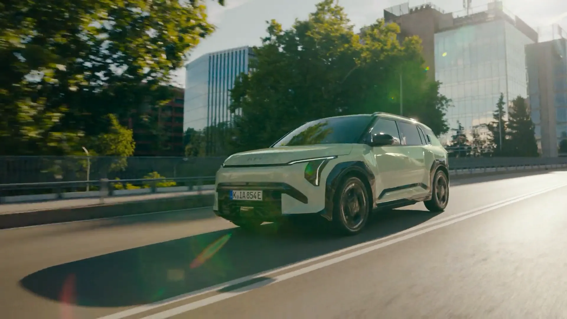 Zelená Kia EV3 v jízdě po mostě ve městě