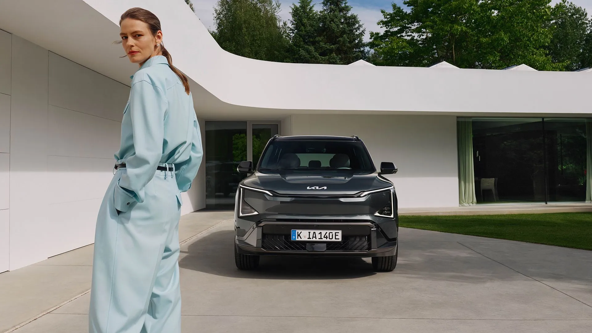 Kia EV5 a žena před moderním domem