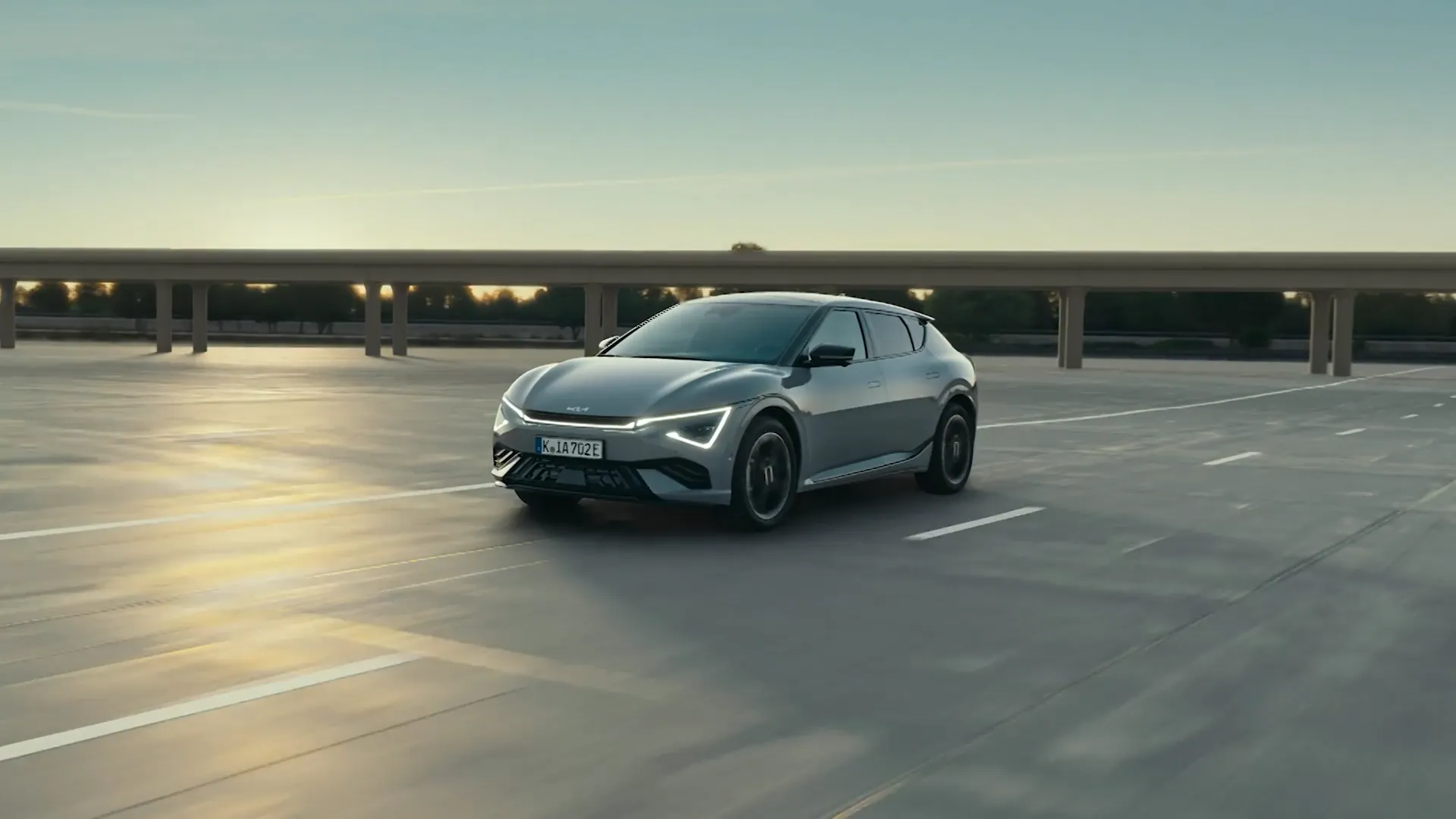 Stříbrná Kia EV6 v jízdě proti zapadajícímu slunci
