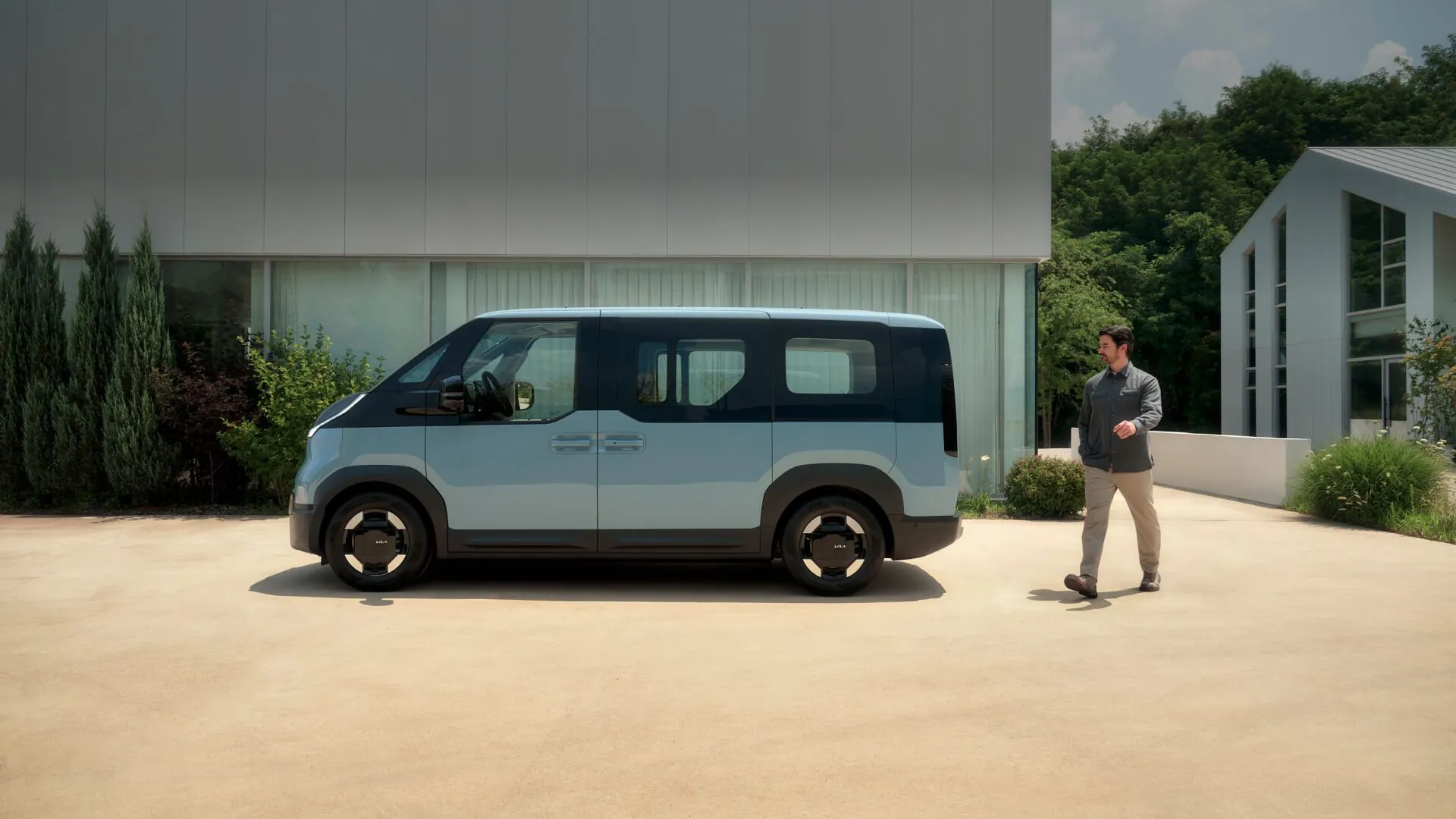 Světle modrá Kia PV5 Passenger z boku před moderním domem