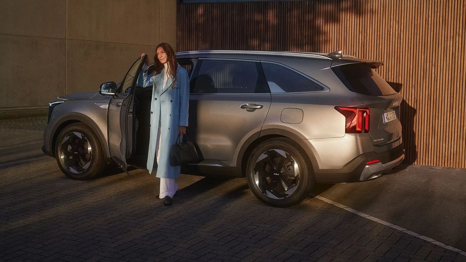 Kia Sorento z boku u dřevěné fasády